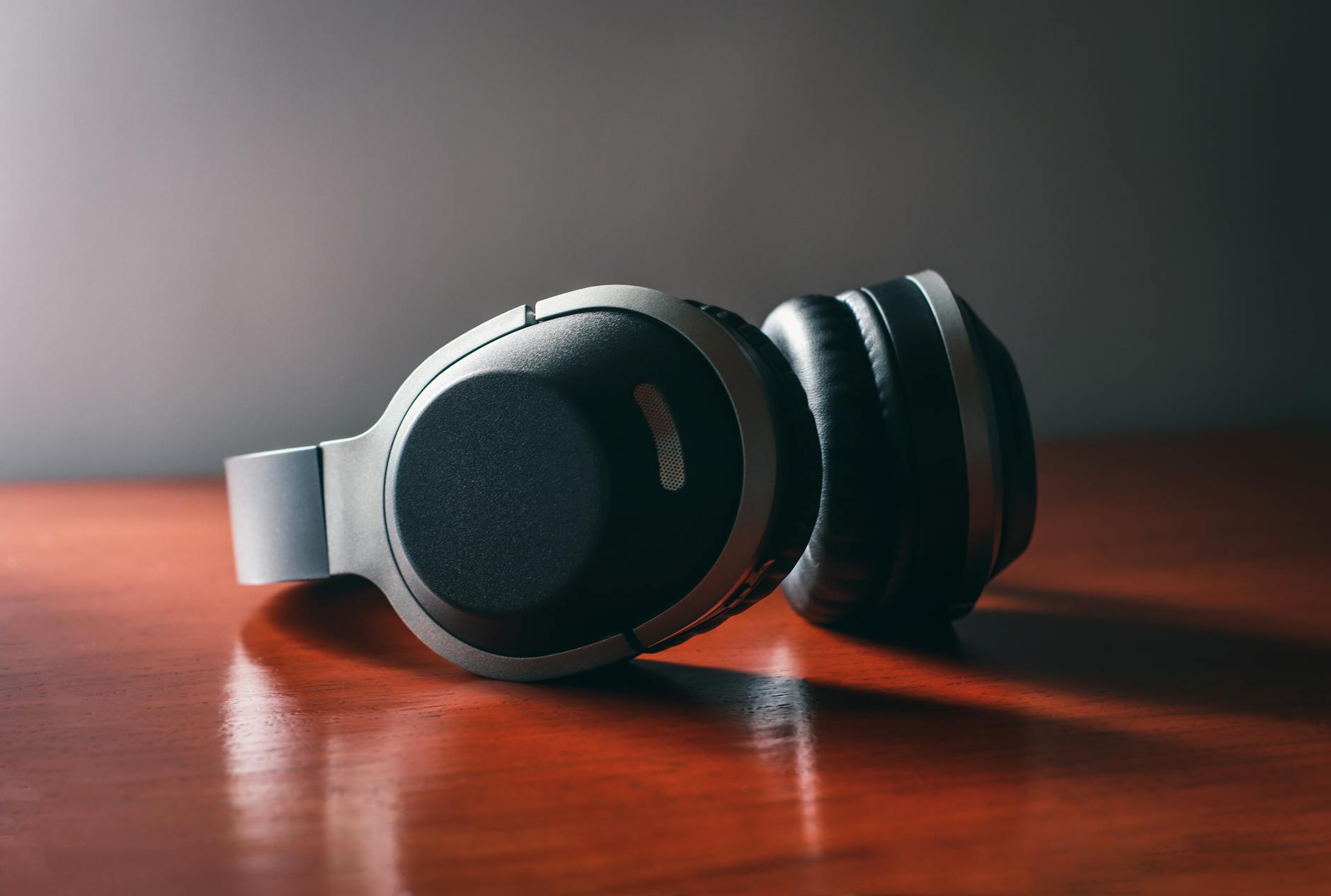 Close-up of modern wireless headphones resting on a polished wooden surface, ideal for tech and lifestyle use.