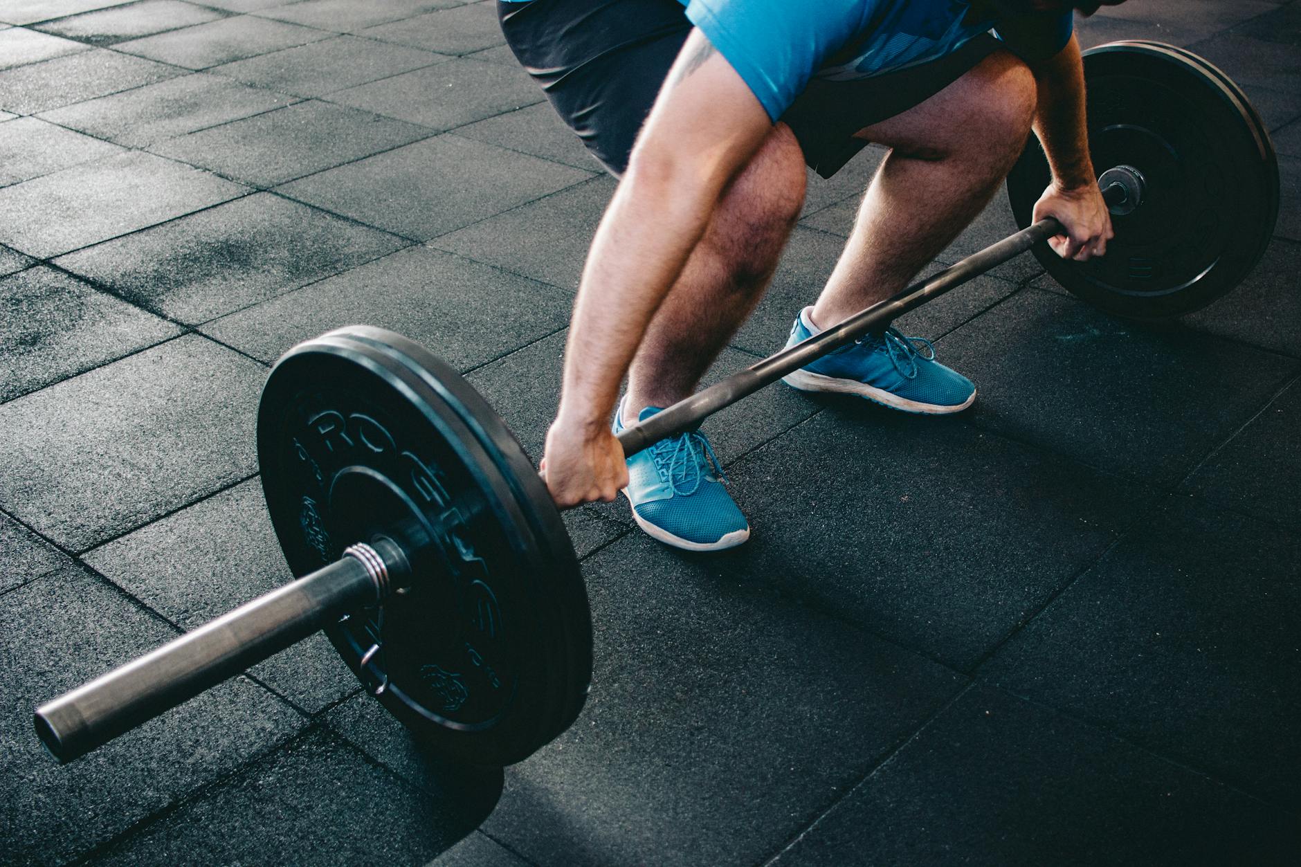 A man deadlifting a barbell indoors showcasing power, fitness, and dedication.