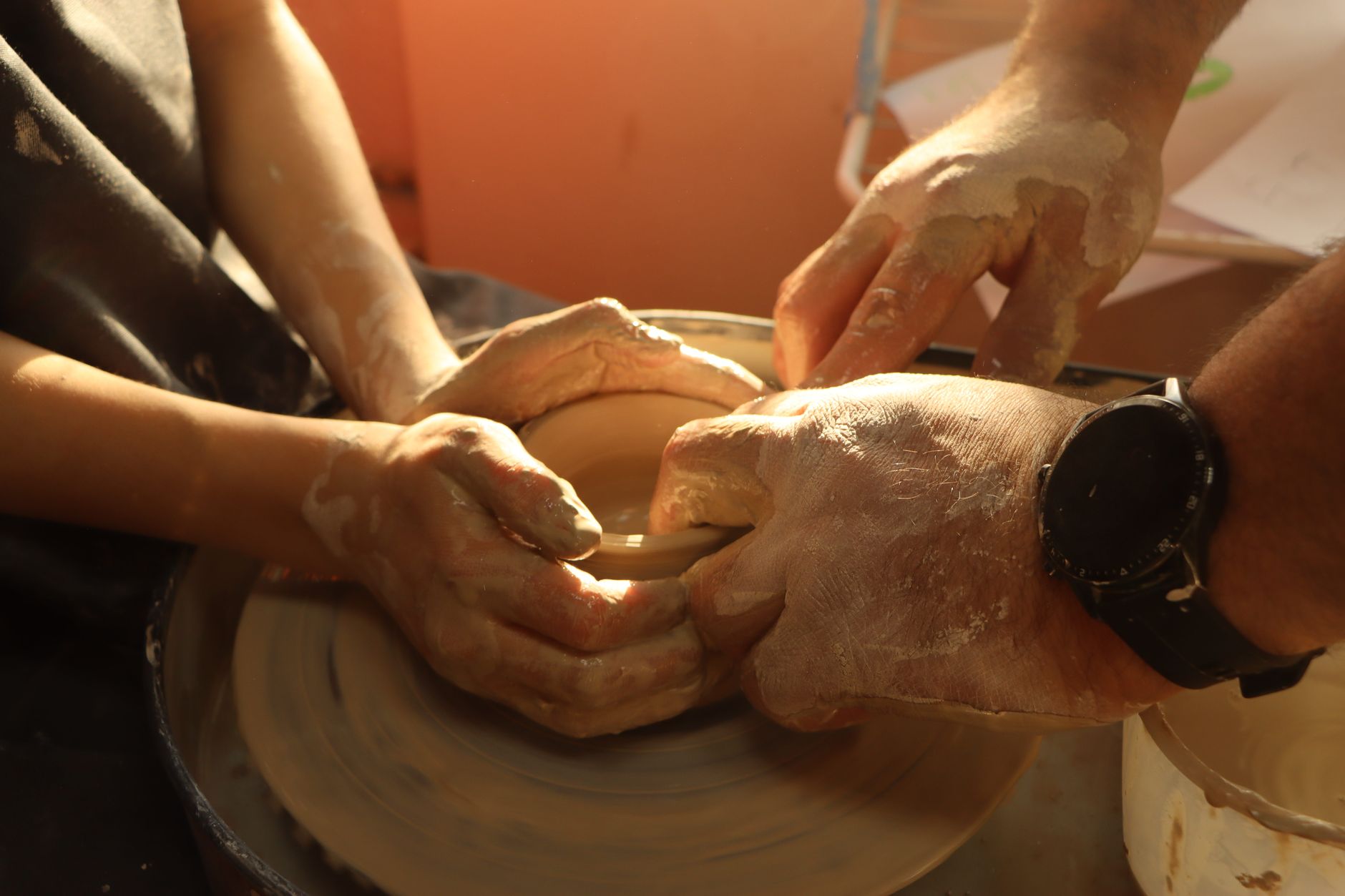 Hands shaping clay on a pottery wheel, capturing the art of pottery making.